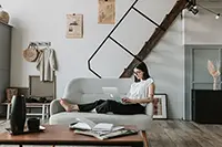 Create a stunning presentation with hiCreo - woman using laptop on love chair in living room with books on coffee table