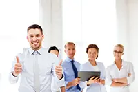 Smiling business professional giving thumbs up, with a confident team in the background, symbolizing successful sales-driven presentations