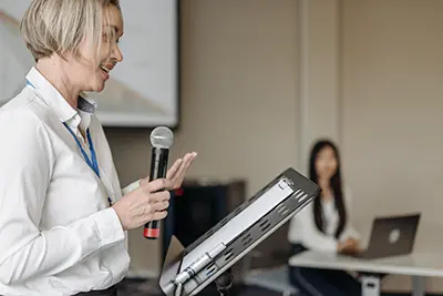 Speaker confidently delivering a presentation using a script as a guide