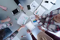 Aerial view of business people brainstorming during a meeting, illustrating the collaborative process of creating startup documents like pitch decks and business plans.